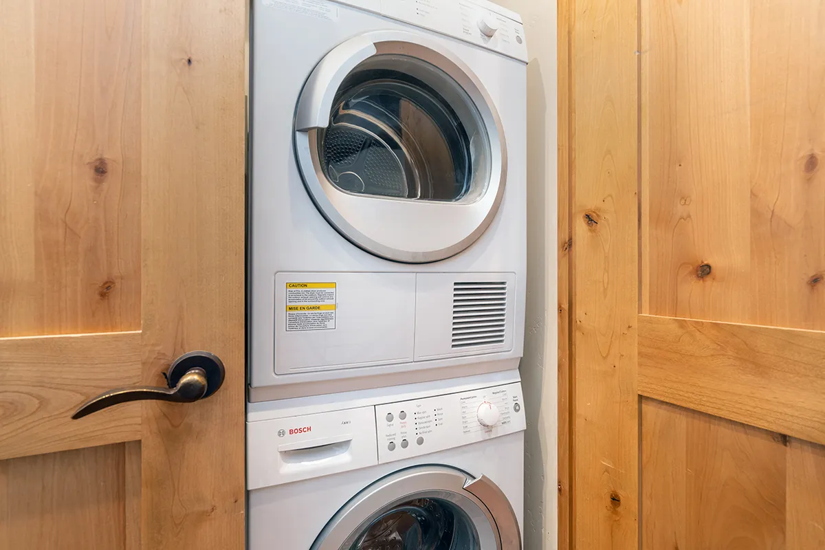 This interior image features a washer and dryer set behind a wooden door, with a tidy, organized laundry area that is functional and easily accessible. The overall atmosphere is clean and practical, visually reinforcing the in-home laundry amenity mentioned in the section.