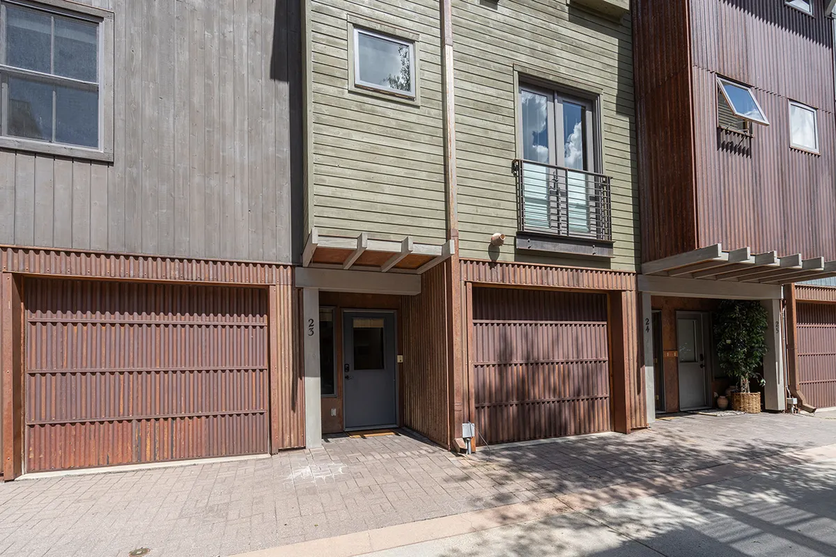 The exterior of the home with a clear view of the balcony from below, featuring a sturdy railing and thoughtfully designed facade. The image also captures the inviting atmosphere of the neighborhood, with textures and materials that hint at modern mountain living.